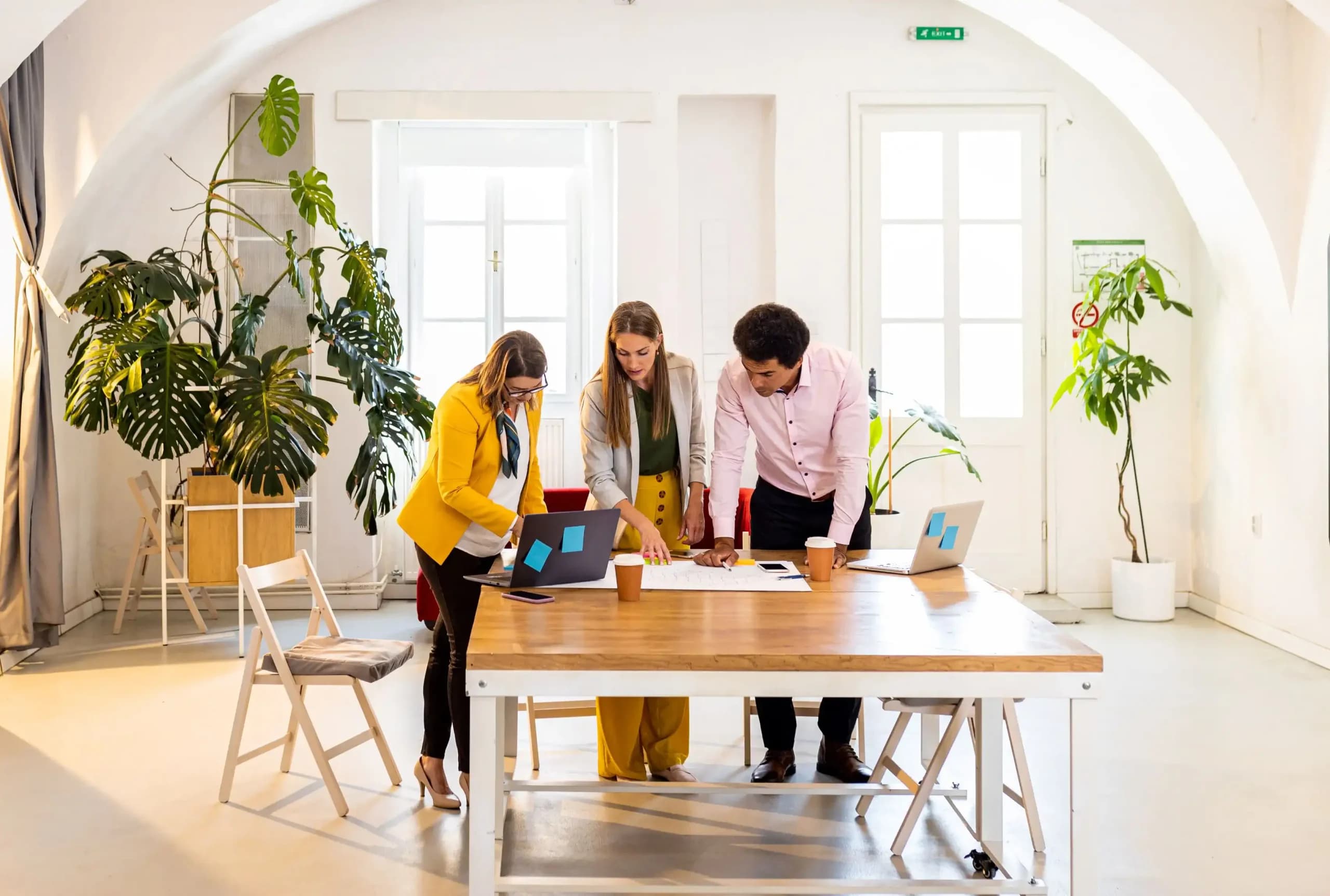 Two women and a man discussing business plan in indoor office.