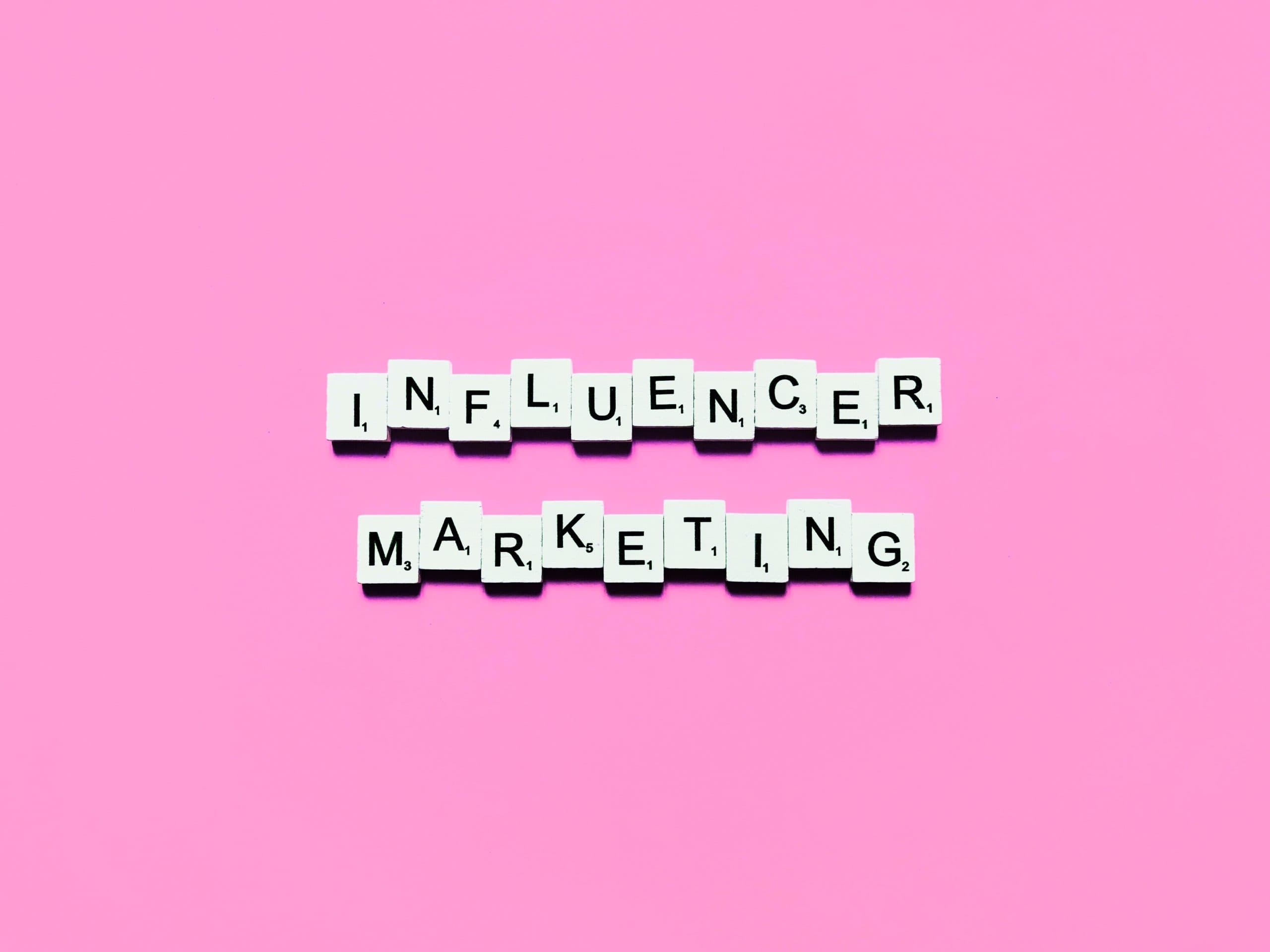 A pink background with words that spell out influencer marketing.